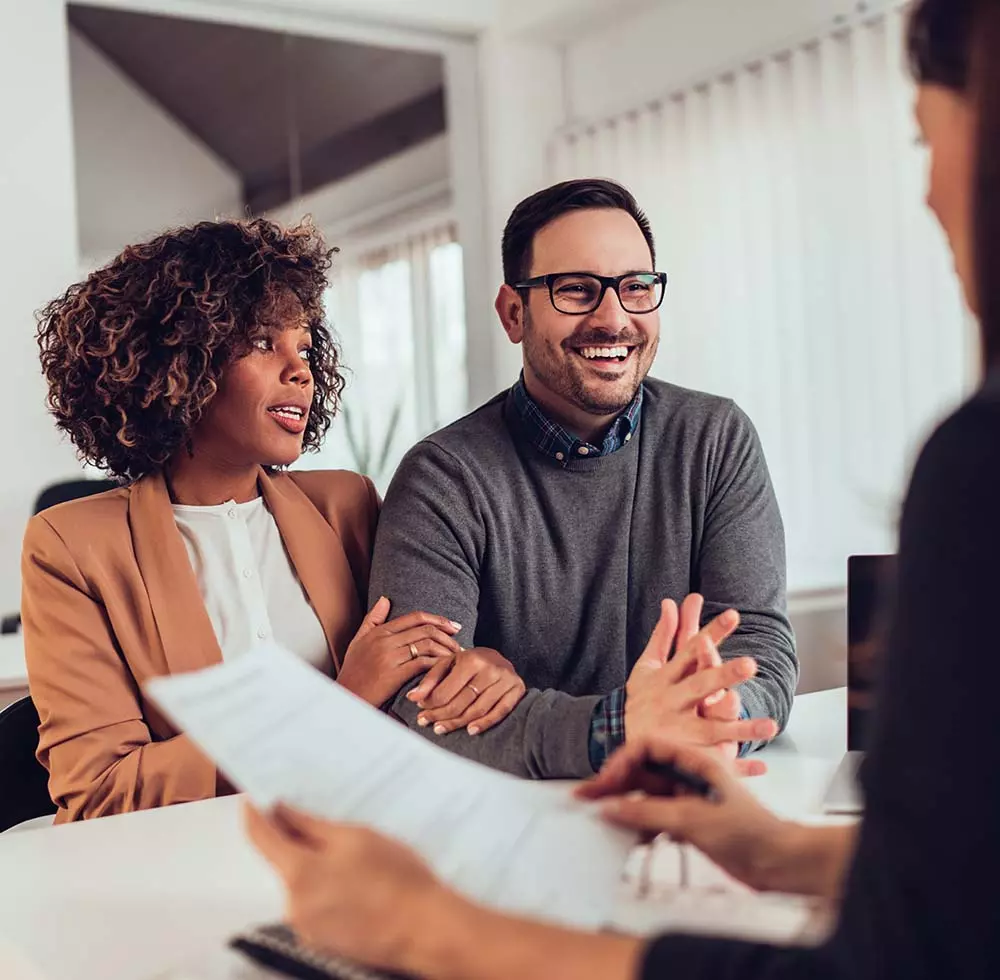 Happy couple talking with a woman who is their lawyer