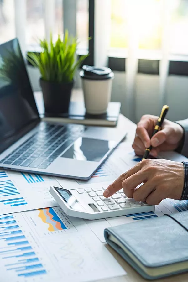 usiness man using calculator with computer laptop, budget and loan paper in office.